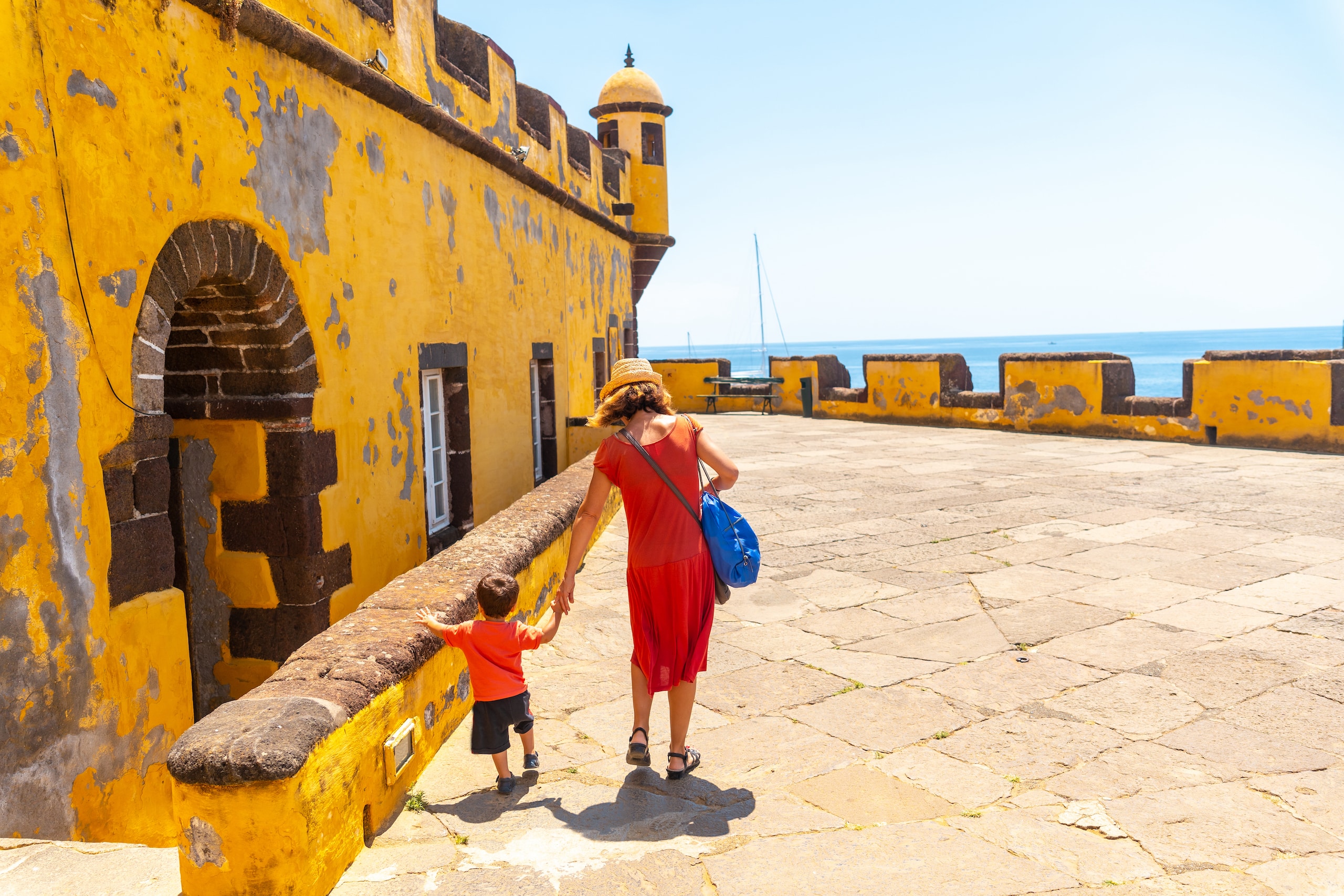 A tourist in summer walking with her baby inside the Forte de Sao Tiago in Funchal. Madeira